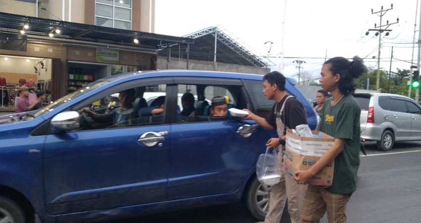 Anggota pecinta Vespa saat membagikan tajkil pada pengguna jalan yang ada di simpang empat Jalan Jhon Aryo Katikli, Ahad (2/4). (F.Diyanti/Gorontalo Post)