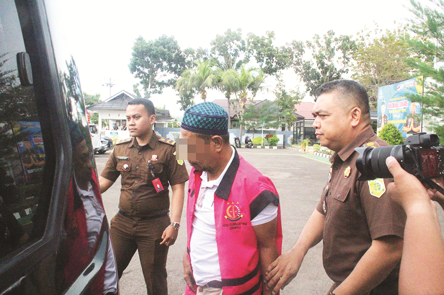 TERSANGKA dugaan korupsi PJUTS Boalemo inisial AU alias Ambo mengenakan rompi tahanan berwarna merah saat digelandang ke mobil tahanan Kejati Gorontalo, Selasa (16/5/23).