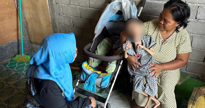 BUTUH BANTUAN :  Putriana Pateda gendong ibunya, saat ditemui di rumah mereka di Desa Permata, Kecamatan Bone, Bone Bolango, baru-baru ini. (foto : dok / gorontalo post)