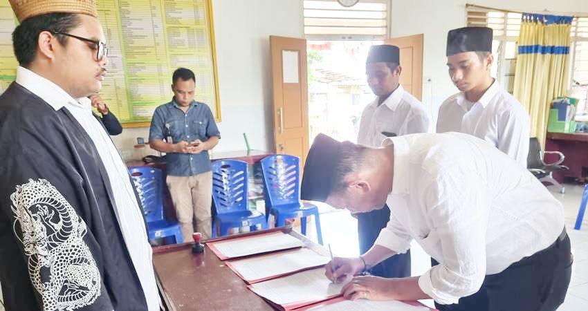 Mantan Ketua Komisi Pemilihan Umum (KPU) Boalemo, Salahudin Pakaya, menandatagani beritaacara pelantikan KPPS di Kota Gorontalo, Kamis (25/1) pekan lalu. (foto : istimewa)