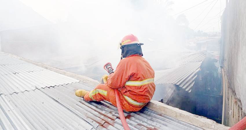PADAT PENDUDUK : Soerang petugas pemadam kebakaran berusaha memadamkan api pada peristiwa kebakaran di Kelurahan Tamulabutao, Kota Gorontalo. (foto : jalal khan/gorontalo post)