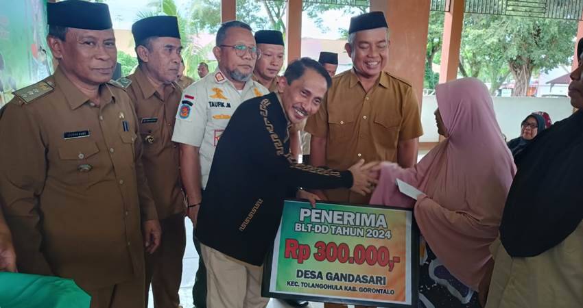 SIMBOLIS. Bupati Gorontalo Nelson Pomalingo saat menyerahkan secara simbolis dana BLT pada salah seorang warga.
