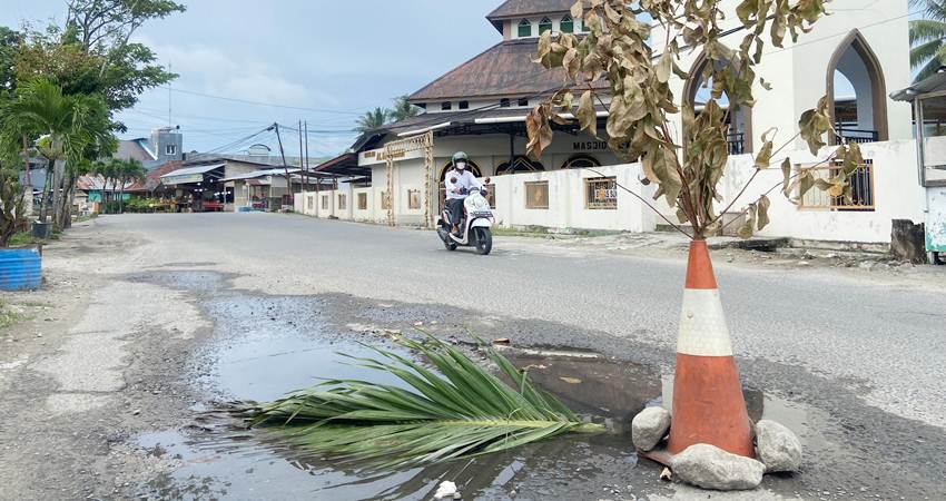 Jalan berlubang yang dibatasi dengan Traffic Cone, yang ditambah dengan ranting pohon kering, Sabtu (1/6/2024) (F. Diyanti/Gorontalo Post)