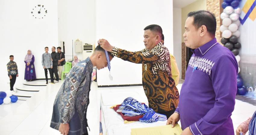 PENAMATAN. Asisten lll Haris S Tome saat mengalungkan piagam pada siswa yang telah tamat belajar selama tiga tahun.