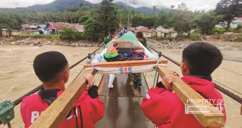 SEORANG Korban luka longsor tambang Suwawa, dievakuasi menggunakan tandu oleh tim evkuasi TNI/Polri saat hendak melintas di jembatan gantung Tulabolo, Suwawa Timur, Senin (8/7) sore. (foto : natha / gorontalo post)