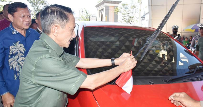 BANNER: Bupati Gorontalo Nelson Pomalingo saat memasangkan bendera merah putih disebuah mobil serta wakil Bupati Hendra Hemeto memasangkan bendera merah putih yang melewati komplek menara