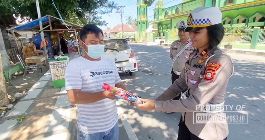Kasat Lantas Polres Pohuwato, Iptu Novika Veronika,S.Tr.K bersama personel, menyerahkan bantuan sosial berupa paket Sembako dan bunga kepada masyarakat yang kurang mampu maupun pengendara yang taat serta tertib berlalu lintas. (F. Zulkifli/ Gorontalo Post)