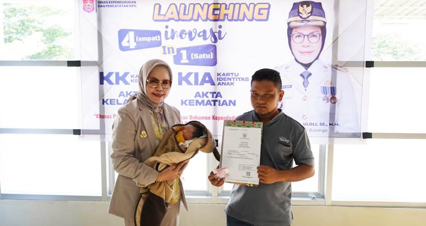 Foto: Merlan Uloli tengah menggendong seorang bayi yang baru saja lahir didampingi ayahnya yang menggenggam akta kelahiran sang anak yang langsung terbit setelah lahir. (Foto: Dok HARGO)