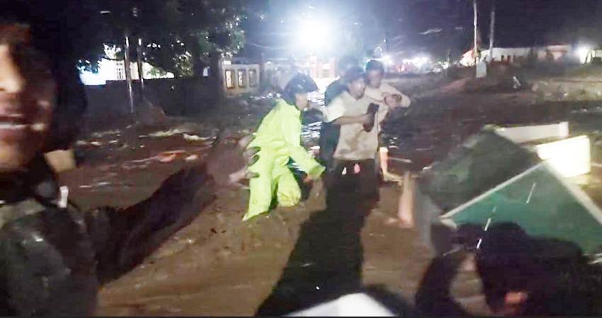 BANJIR BANDANG - Warga saling membantu saat melintas di Jln Trans Sulawesi Desa Huangobotu, Kecamatan Kabila Bone, Bone Bolango, Senin (21/10) malam, karena banjir bandang dengan debit air cukup deras. (foto : tangkapan layar )