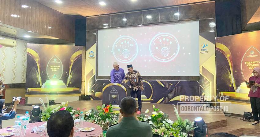 Penjabat Gubernur Provinsi Gorontalo Rudy Salahuddin, didampingi oleh Kepala Kanwil Ditjen Perbendaharaan Provinsi Gorontalo Adnan Wimbyarto, menyerahkan, Kamis (19/12/2024) (F. Diyanti/Gorontalo Post)