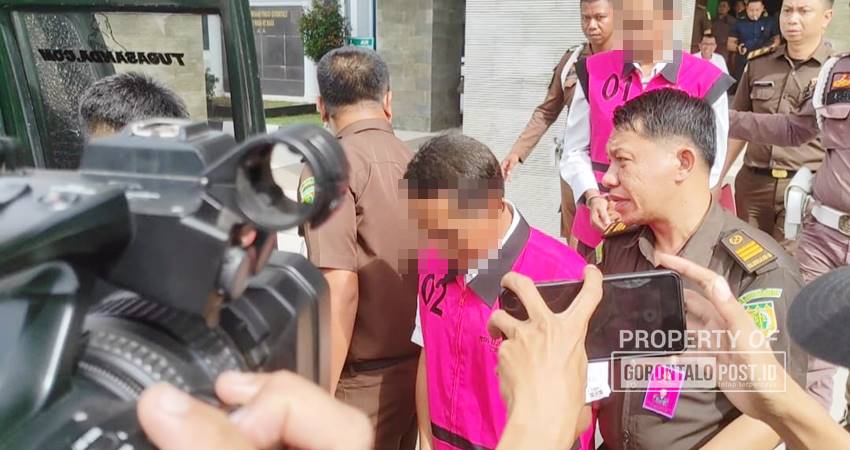 Tersangka proyek kanal Tanggidaa mengenakan rompi tahanan warna merah jambu saat digiring ke mobil tahanan, Kamis (5/12/2025). (Foto: Roy/Gorontalo Post)