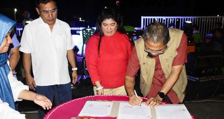 Pj Wali Kota Gorontalo, Ismail Madjid ketika menandatangani dokumen tanda diresmikannya 32 PSU dan lampu jalan di Santorini, Jumat (3/1/2025) malam. (Foto: Prokopim)