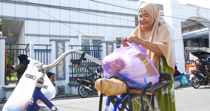 PENUHI KEBUTUHAN : Mariam Ahmad salah satu warga Desa Pauwo dengan sepeda tuanya, datang ke kantor Kejaksaan Tinggi Gorontalo untuk berbelanja di pasar murah, Ahad (16/3). (foto : nova / diskominfotik)