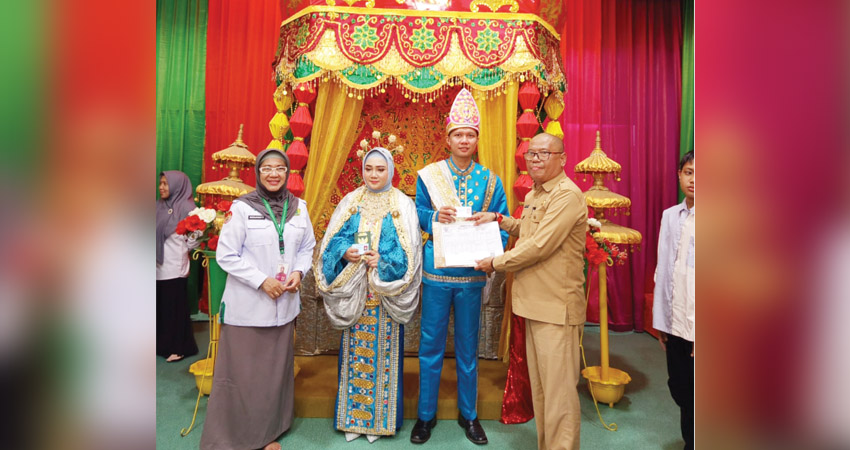 Kepala Disdukcapil Kota Gorontalo, Yusrianto Kadir didampingi Kakan Kemenag Kota Gorontalo, Misnawaty Tuna, tengah menyerahkan dokumen kependudukan kepada pengantin, Selasa (10/6/2025). (Foto: Kominfo)