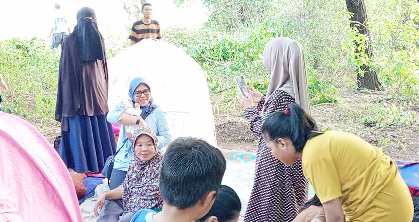 NAIK GUNUNG - Anggota DPRD Provinsi Gorontalo, Femi Udoki menggendong seorang bayi di lokasi pengungsian warga di Desa Bintalahe, Kabila Bone, kemarin. (foto : istimewa)