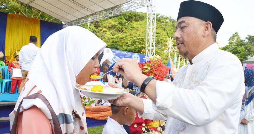 Hamim Pou menyuapi salah satu anak yatim dalam kegiatan Festival Anak Yatim di Bone Bolango saat dirinya menjabat Bupati. (foto : istimewa)