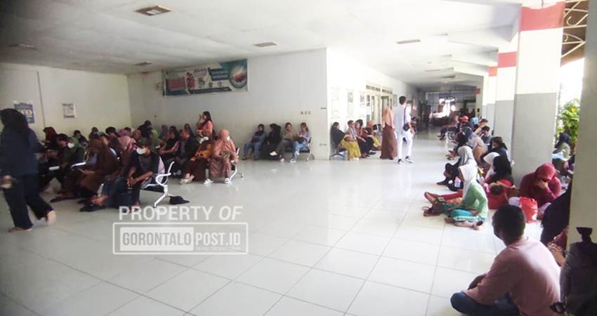 Pasien rawat jalan yang tidak mendapat tempat duduk terpaksa harus duduk di lantai akibat lonjakan drastic jumlah pasien di RSAS Kota Gorontalo, Rabu (23/7/2025). (Foto: Roy/Gorontalo Post).