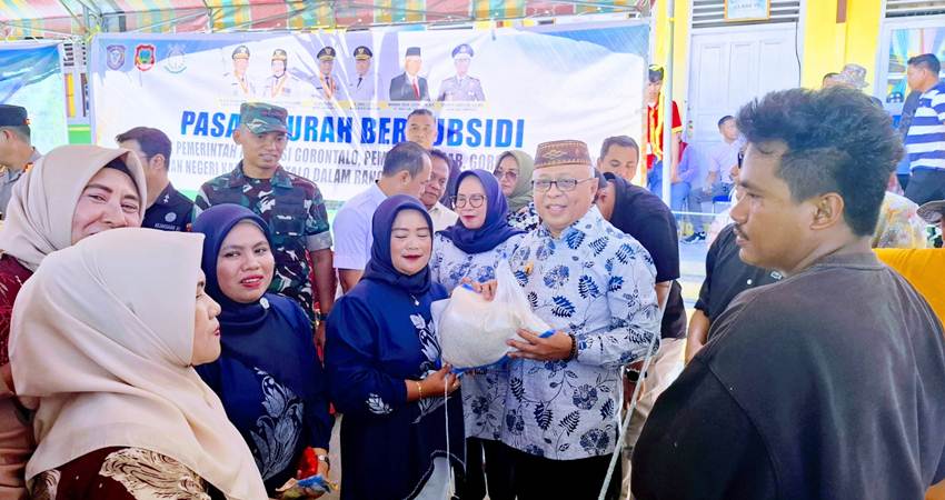 LAYANI. Bupati Gorontaalo Sofyan Puhi didampingi Ketua TP PKK Maryam Puhi Pago saat melayani para masyarakat yang membeli di pasar murah