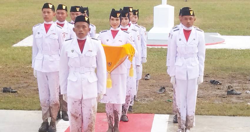 PENUH SEMANGAT - Paskibraka tingkat Kecamatan Boliyohuto, Kabupaten Gorontalo penuh semangat menunaikan tugas mengibarkan Merah Putih di tengah lumpur, saat HUT ke 80 RI, Ahad (17/8). (foto : istimewa)