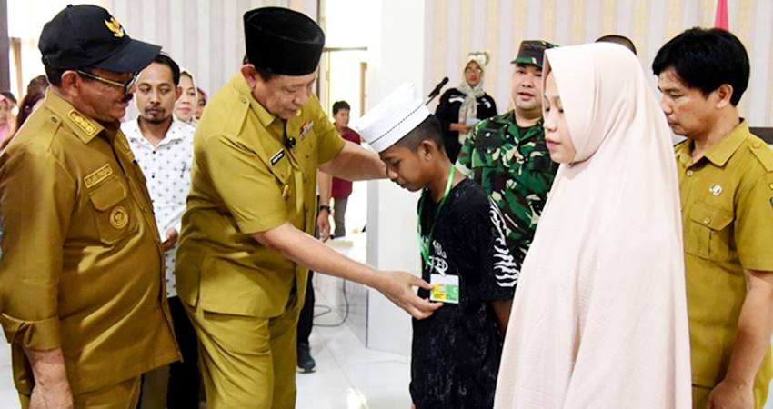 Gubernur Gusnar Ismail mengalungkan tanda peserta MPLS kepada siswa Sekolah Rakyat Terintegrasi 71 di Kecamatan Botumoito, Kabupaten Boalemo, Selasa (30/9). (Foto : Haris/diskominfotik)