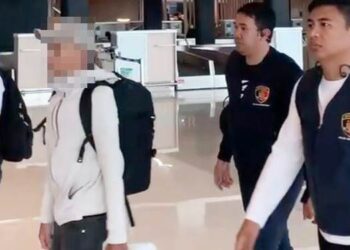 Tersangka dugaan korupsi proyek pemeliharaan Jalan Nani Wartabone Kota Gorontalo inisial RA (pakai topi) dikawal penyidik Ditreskrimsus Polda Gorontalo saat berada di Bandara Sultan Hasanudin Makassar.