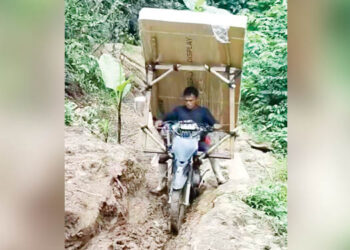 BANTUAN PRESIDEN- Urianto Daud pengemudi ojek dengan sangat hati-hati melintasi akses Pinogu saat mengangkut Smart TV bantuan Presiden dengan ojek yang dimodifikasi khusus. (foto: tangkapan layar)