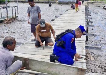 Kondisi jalan berbahan papan kayu yang sudah mulai rusak di Desa Torosiaje, Kecamatan Popayato, Kabupaten Pohuwato, diperbaiki warga secara gotong royong dibantu petugas Polairud Polda Gorontalo, Rabu (15/10/2025).