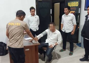 Oknum ASN Gorut inisial MR mengenakan stelan kemeja lengan panjang berwarna putiu saat menjalani proses pemeriksaan kesehatan jelang penahanan yang dilakukan penyidik Reskrimum Polda Gorontalo Senin (24/11/2025) (Foto: Humas Polda Gorontalo/ for Gorontalo Post).