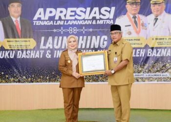 Kepala BKKBN Provinsi Gorontalo Diano Tino Tandaju saat menyerahkan penghargaan dari BKKBN RI kepada Wakil Gubernur Gorontalo Idah Syahidah Rusli Habibie Bunda Akselerasi Penurunan Stunting di Provinsi Gorontalo. (Foto – Nova/Diskominfotik).