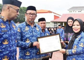 Wagub Idah Syahidah Rusli Habibie menyerahkan penghargaan The Best ASN of The Month pada apel akbar HUT ke-54 Korpri dan HUT ke-25 Provinsi Gorontalo di halaman Museum Purbakala, Senin (1/12). (Foto : Haris/diskominfotik)