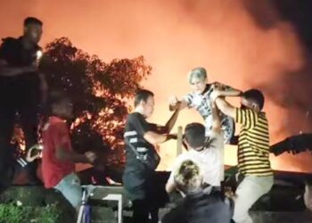 EVAKUASI LANSIA: Warga gotongroyong melakukan evakuasi terhadap Lansia yang terjebak dari dalam gedung Panti Werdha Damai Ranomuut, Manado, yang terbakar, Ahad (28/12) malam. (foto: tangkapan layar/video-facebook @tonny rarung)