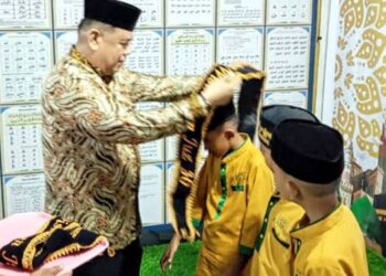 WISUDA. Kabag Kesra saat mengalungkang selempang pada para wisudawan.