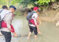 Petugas kepolisian Brimob Polda Gorontalo membantu warga, khususnya anak-anak sekolah, menyeberangi sungai akibat putusnya jembatan gantung yang menjadi akses utama masyarakat, Selasa (14/01/2026).
