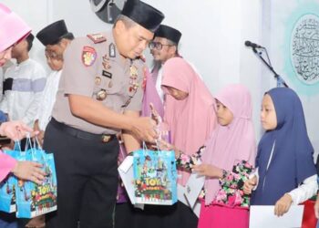 Kapolres Pohuwato, AKBP H. Busroni,S.I.K.,M.H. didampingi Ketua Bhayangkari Cabang Pohuwato, menyerahkan santunan kepada anak yatim.