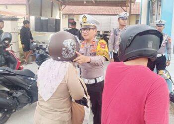 Kasat Lantas Polres Pohuwato, Iptu Jefriansyah Tangahu,S.H. bersama personel, membagikan helm gratis kepada pengendara sepeda motor di saat pelaksanaan Operasi Keselamatan Otanaha 2026. (F. Zulkifli/ Gorontalo Post)